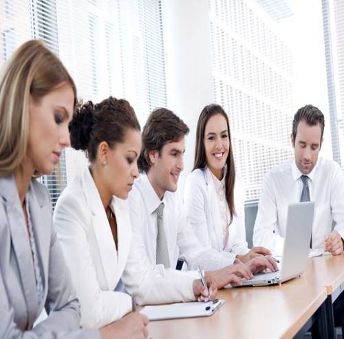 Healthcare professionals discussing a laptop and clipboard